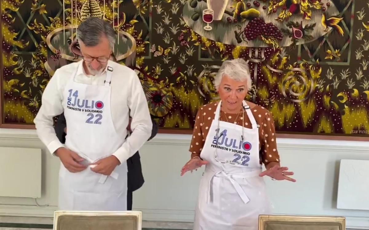 Con mandiles con la leyenda: “14 de julio feminista y solidario 22” se les ve preparar la receta y posteriormente degustar el platillo. | Captura