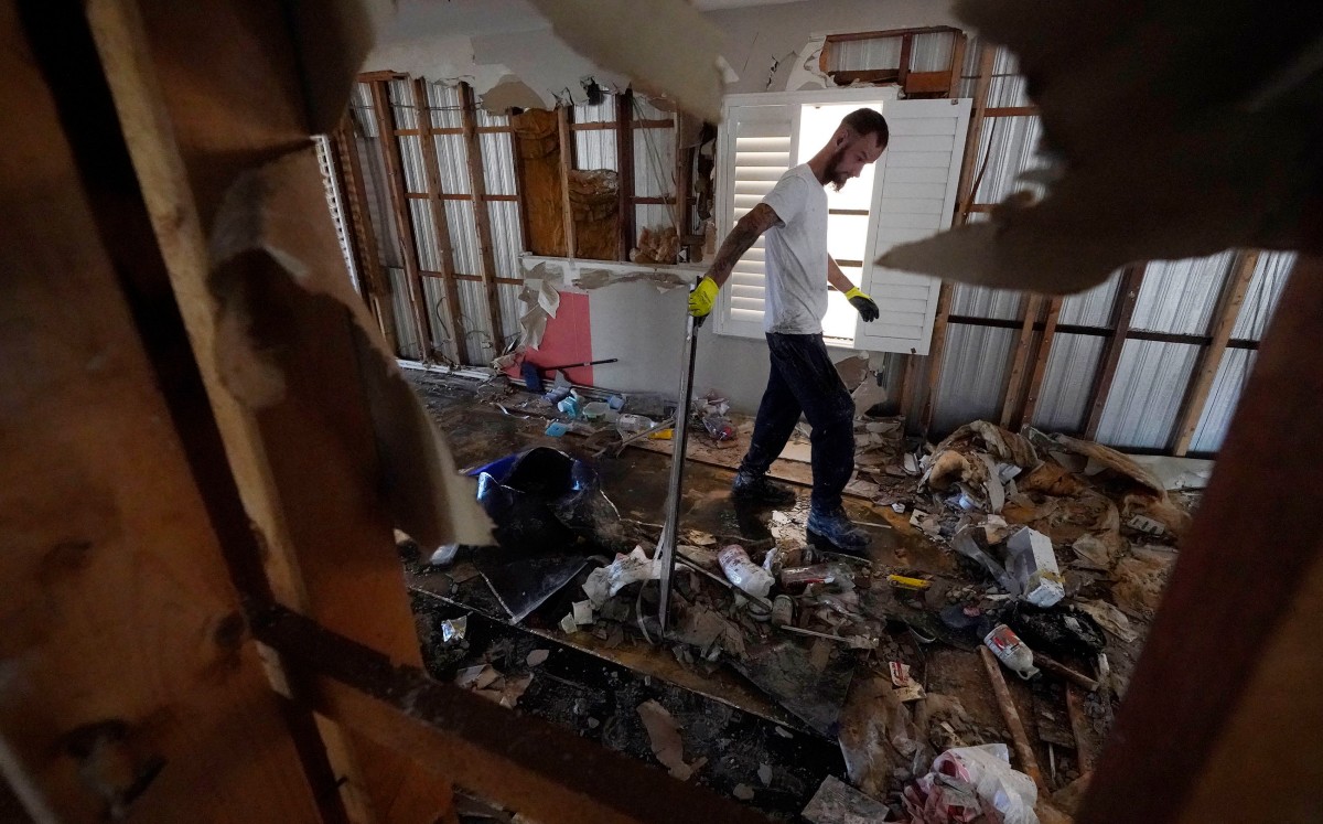 Un trabajador recoge escombros de una casa rodante que resultó dañada por el huracán 'Ian'. | AP
