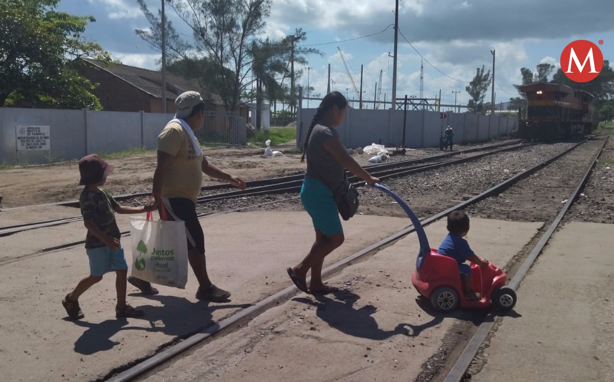 Familias cruzan la vía del tren en Ciudad Madero.
