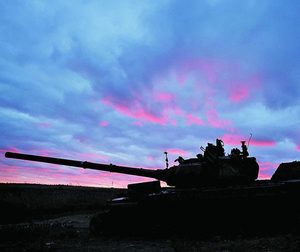 Un hombre camina al atardecer cerca de un tanque destruido en Ucrania. C. Kilcoyne/Reuters