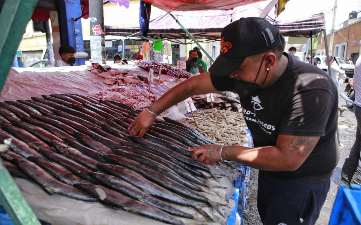 Un hombre prepara pescado para su venta. El maratón Guadalupe-Reyes-Candelaria será muy caro para los poblanos |  Andrés Lobato