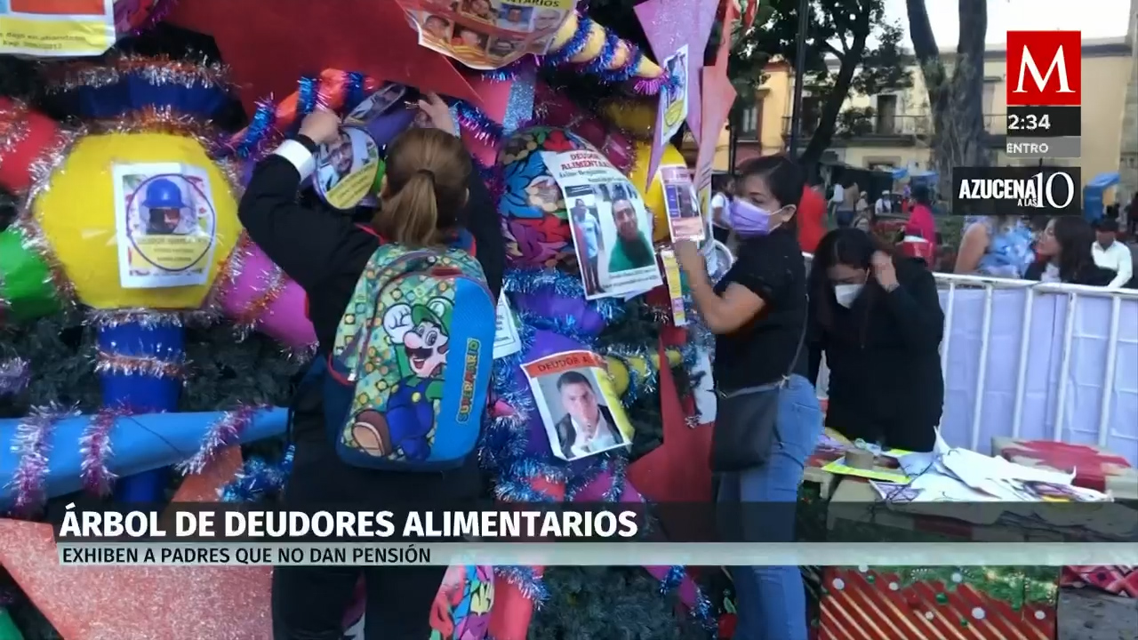 Mujeres oaxaqueñas colocan árbol de navidad con imágenes de deudores alimentarios