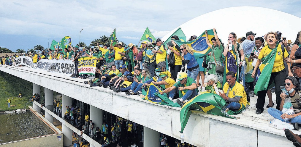 Partidarios exaltados del ex presidente Jair Bolsonaro se instalan en el tejado del Congreso Nacional tras invadirlo con violencia, ayer, en Brasilia.