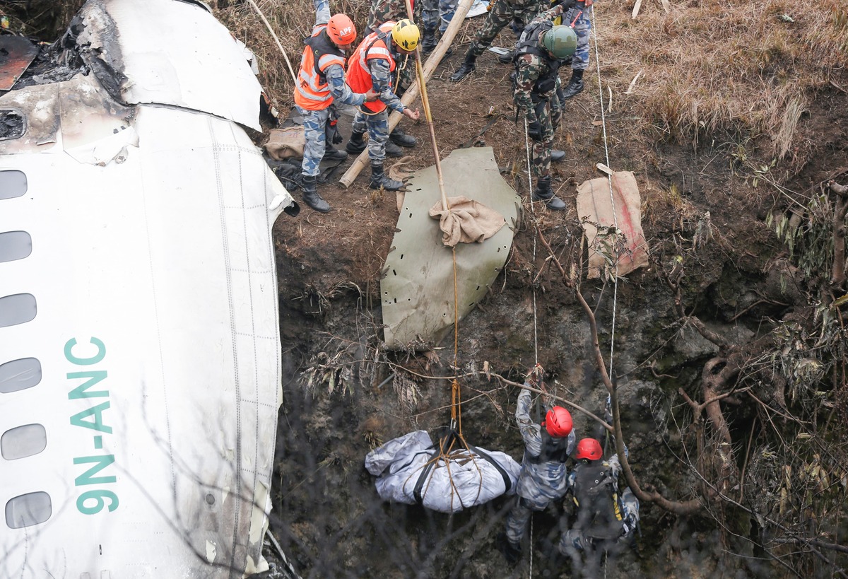 Un equipo de rescate recupera el cuerpo de una víctima del lugar donde se estrelló un avión operado por Yeti Airlines. (Reuters)