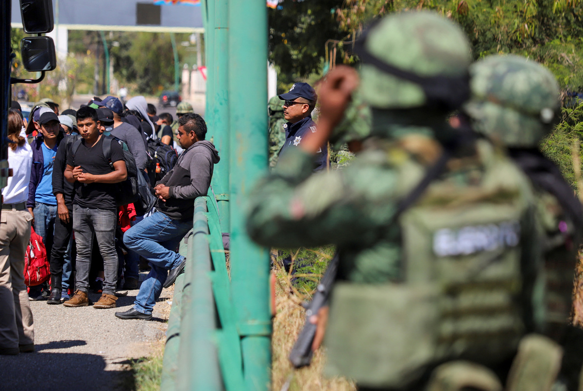 Autoridades vigilan a migrantes mientras descienden de un tractocamión. (Reuters)
