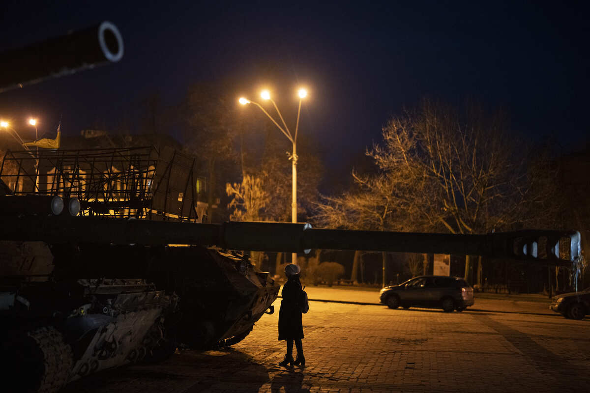 Una mujer parada frente a vehículos blindados y tanques rusos destruidos en el centro de Kiev, Ucrania. (AP)