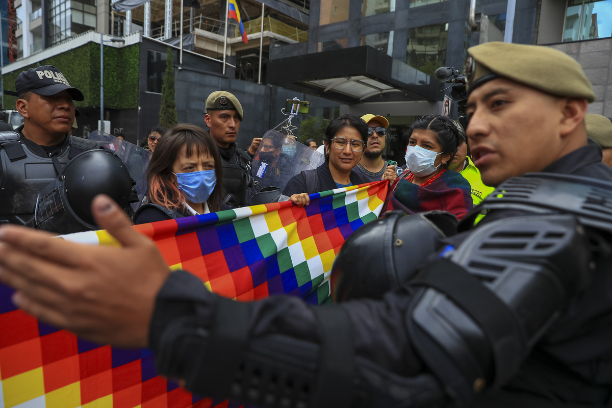 Un policía vigila a miembros de la confederación de nacionalidades indígenas del Ecuador (EFE)