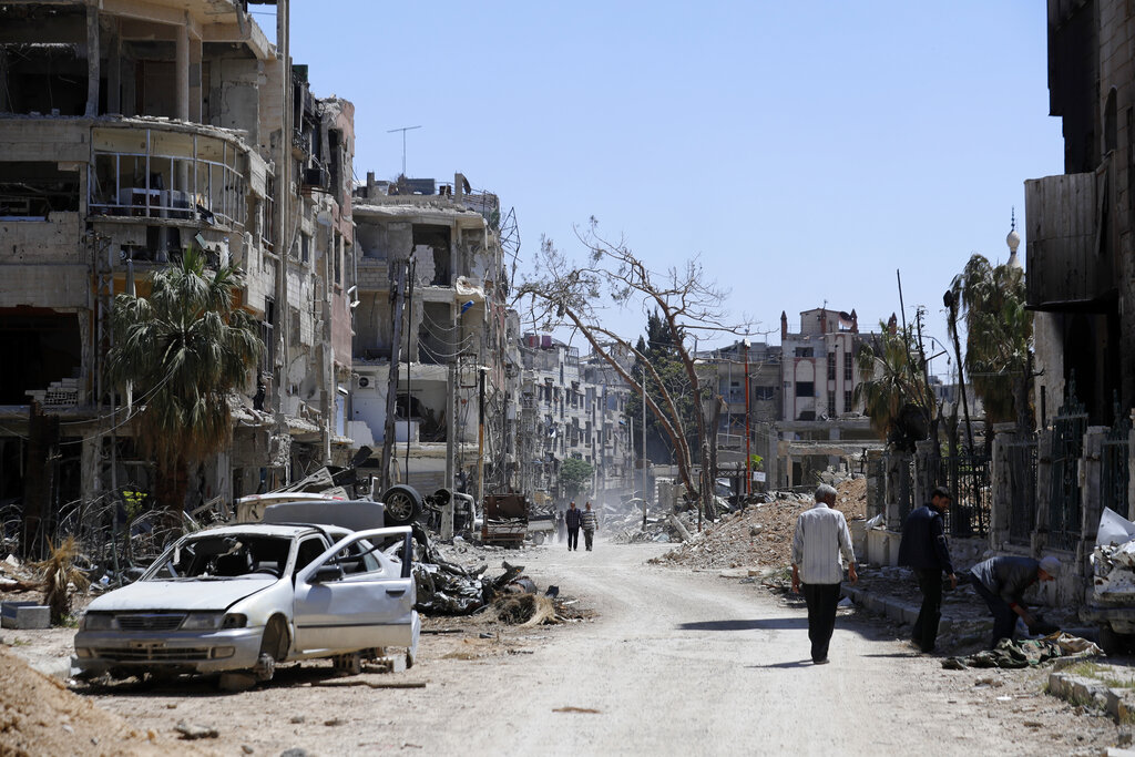 Personas caminan por la destruida localidad de Douma, el escenario de un presunto ataque con armas químicas en Siria. (AP)