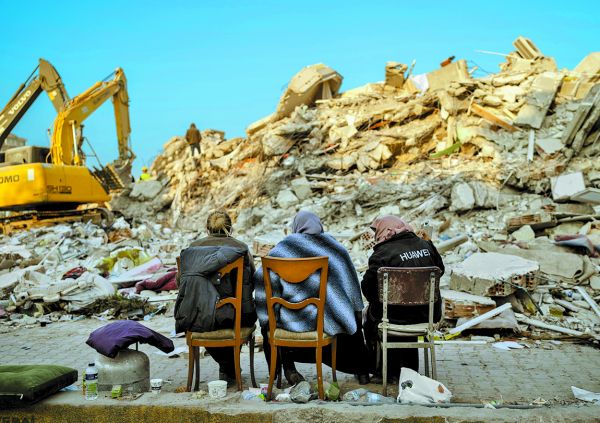 Mujeres se sientan frente a los escombros de edificios en Antakya. AP