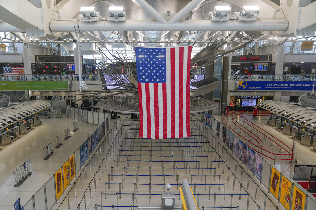 Una bandera estadounidense cuelga sobre la Terminal 1 prácticamente vacía en el Aeropuerto Internacional John F. Kennedy se Nueva York. (AP)