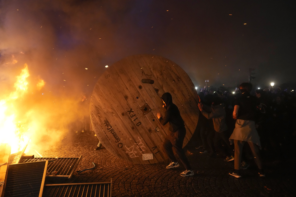 Manifestantes empujan una rueda de madera durante una protesta, el viernes 17 de marzo de 2023, en París. (AP)