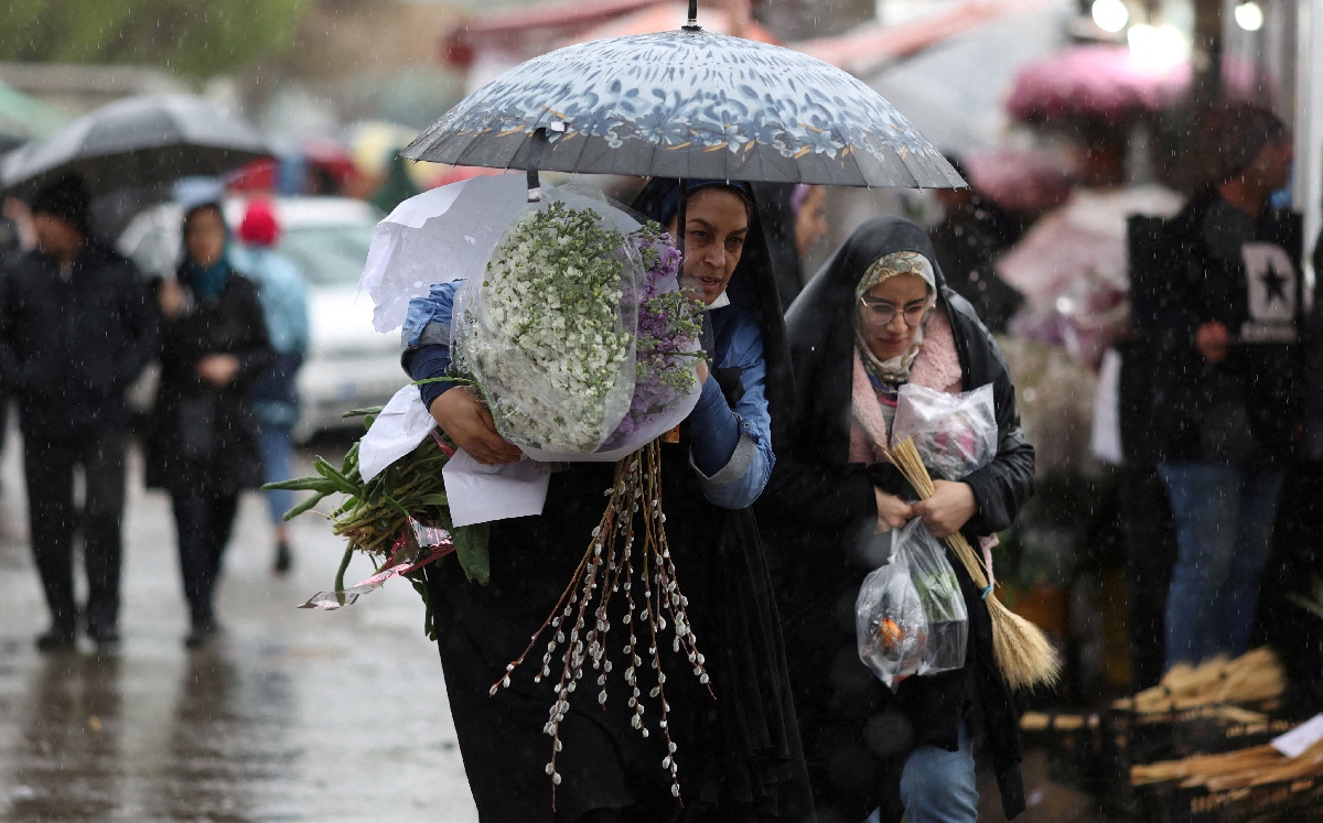 Mujeres iraníes caminan bajo la lluvia en un mercado de flores, antes de Nowruz, el Año Nuevo iraní. | Reuters