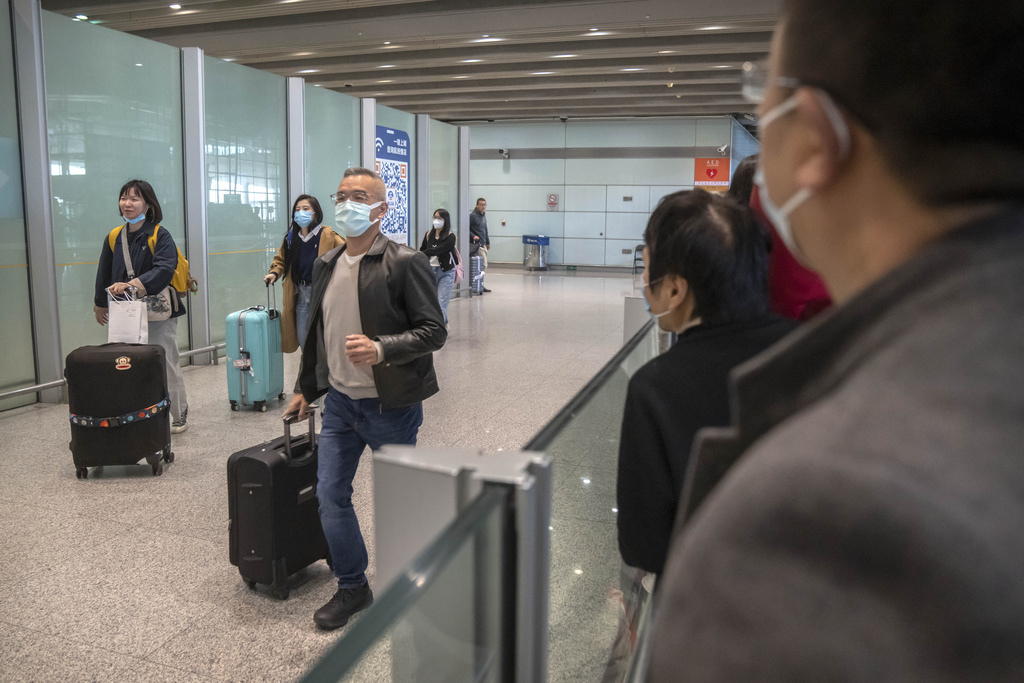 Viajeros con mascarilla caminan por la zona de llegadas internacionales del Aeropuerto Internacional de Beijing | AP
