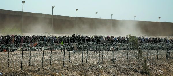 Decenas de indocumentados esperan frente al muro fronterizo que separa a Ciudad Juárez de esa urbe estadunidense. AP