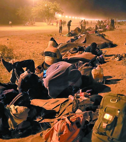 Indocumentados esperan en la puerta 42 del muro fronterizo. EFE