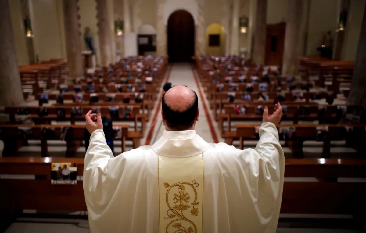 Sacerdote católico frente a iglesia vacía (Reuters)