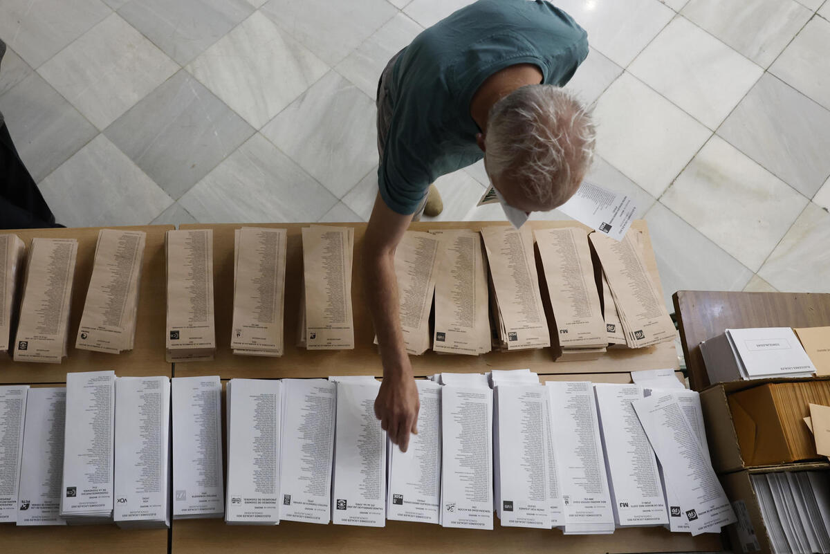 Un hombre escoge entre las papeletas para votar en el colegio Nuestra Señora del Buen Consejo. | EFE
