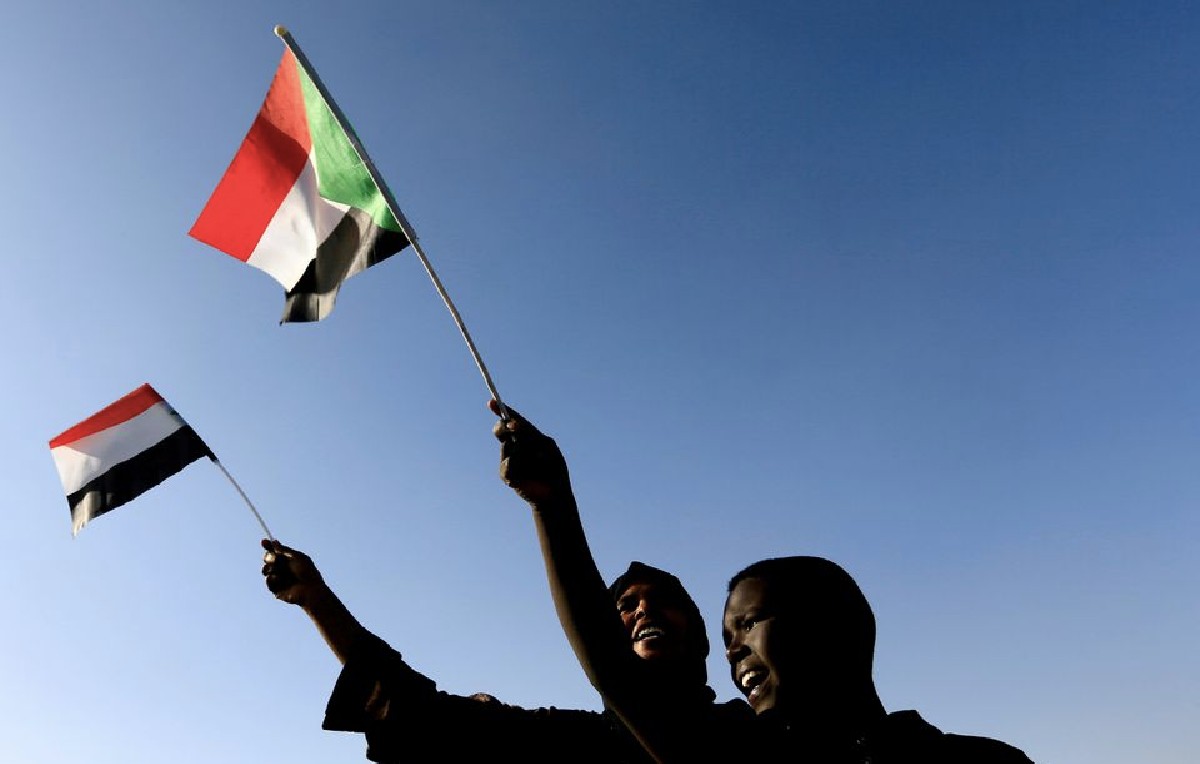 Sudaneses ondeando su bandera durante el aniversario del su revolución (Reuters)