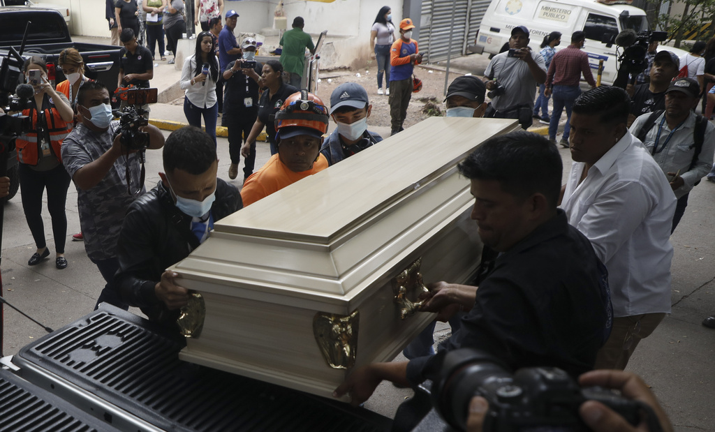 Varias personas colocan un ataúd que contiene los restos de una presa en un auto fúnebre en Tegucigalpa, Honduras | AP