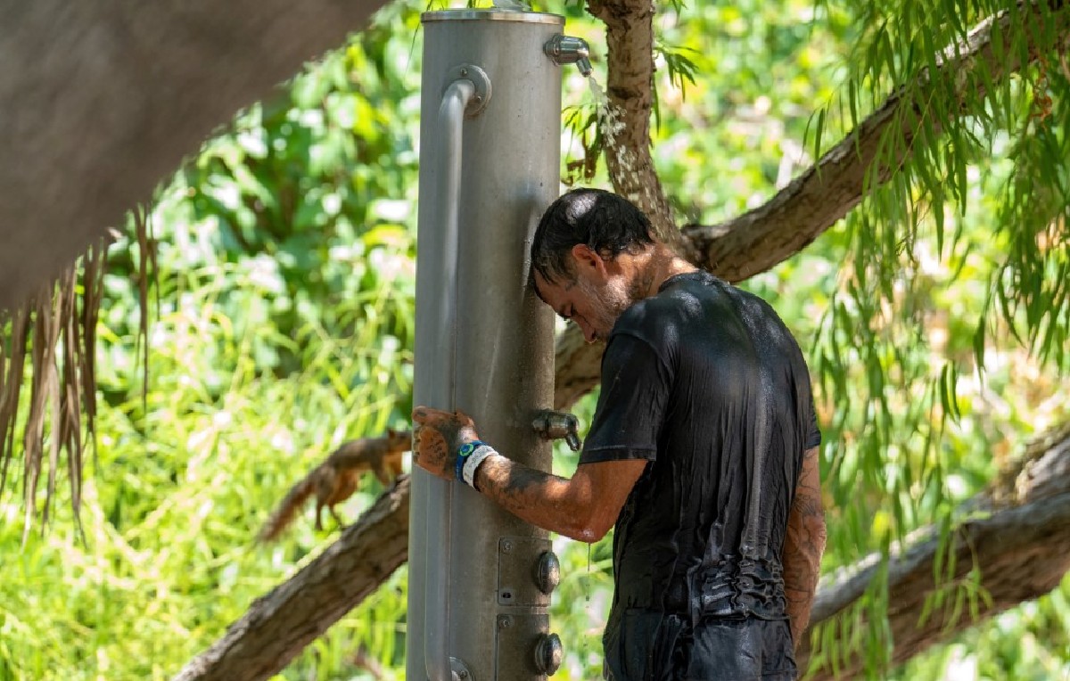 Hombre refrescándose con bebedero en Houston ante ola de calor (AFP)