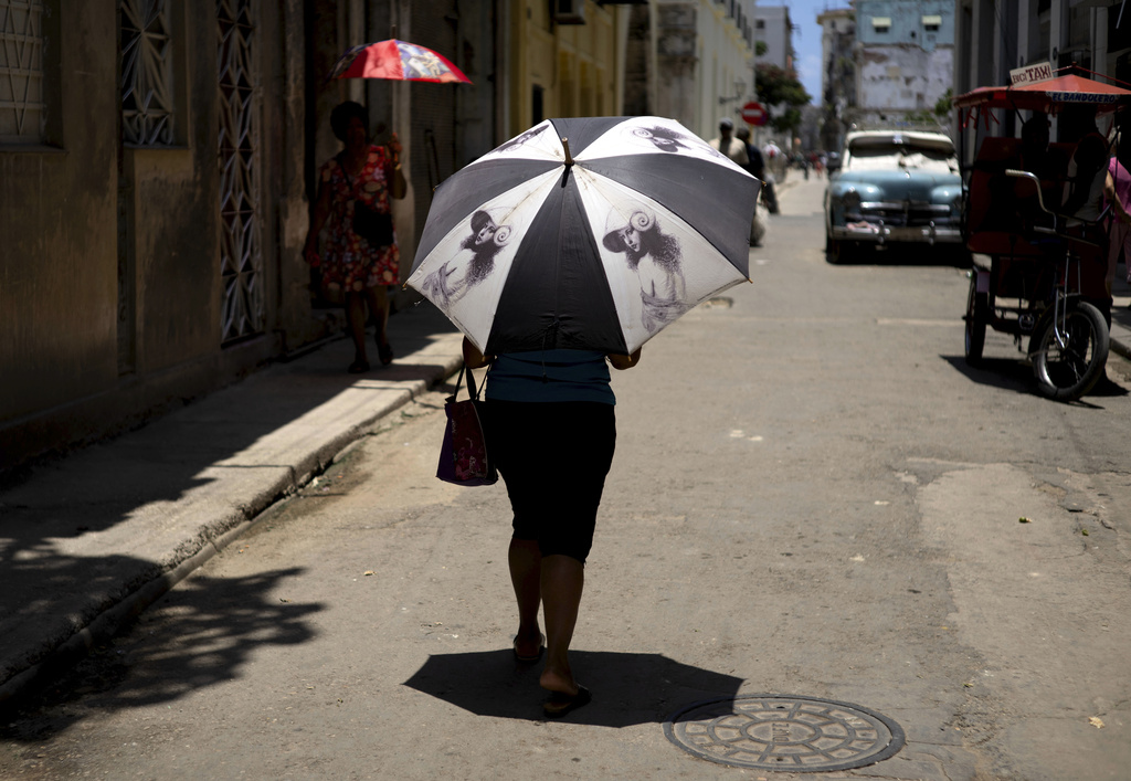 Una persona se protege del calor bajo una sombrilla en una calle de La Habana, Cuba | AP