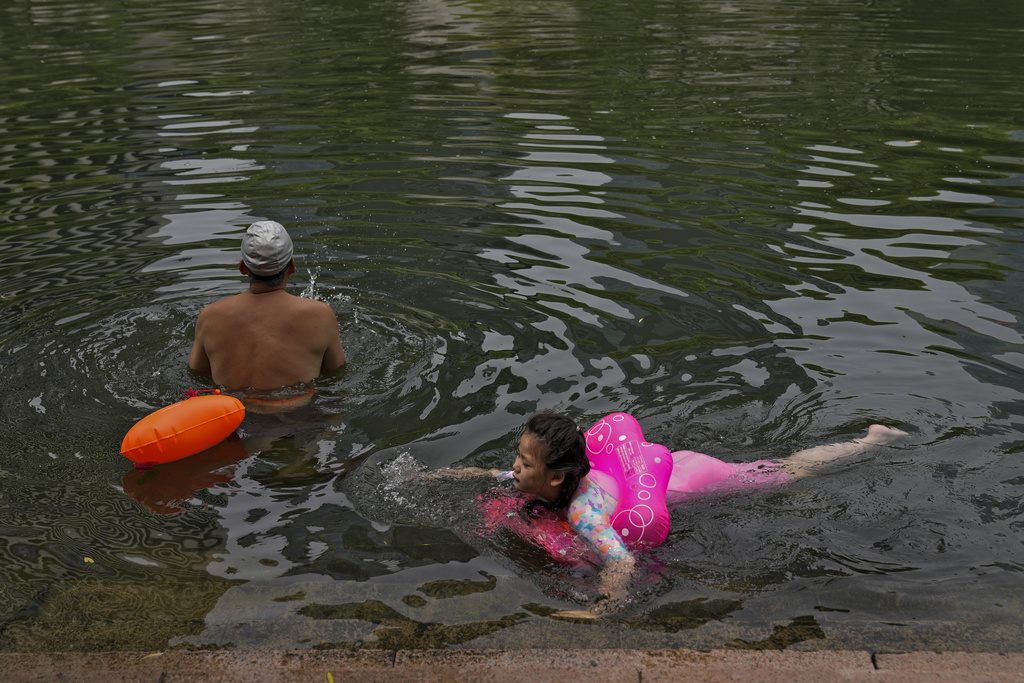 Vecinos nadando en un canal urbano para refrescarse en un día inusualmente caluroso en Beijing | AP