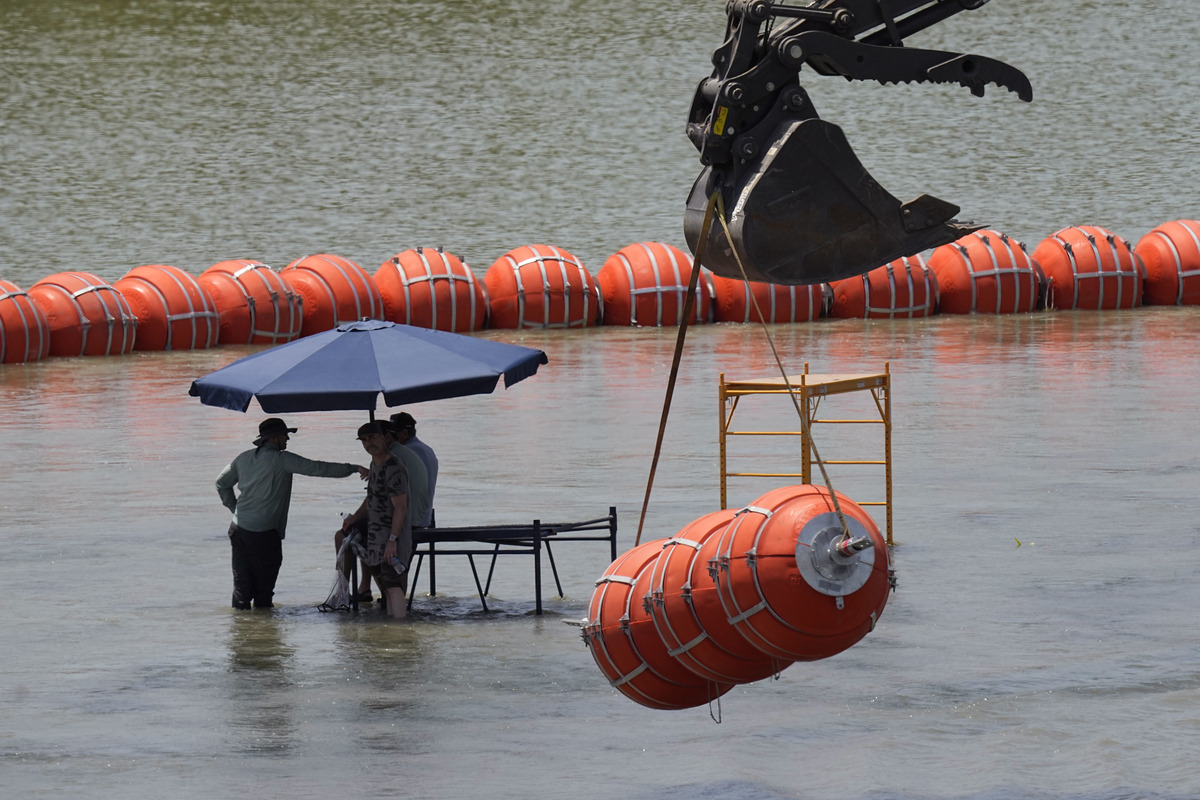 Trabajadores toman un descanso de colocar boyas para que sean utilizadas como barrera fronteriza en el río Bravo. (AP)