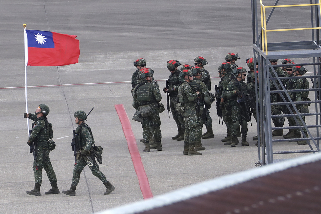 Soldado taiwanés sostiene una bandera de Taiwán cerca de un grupo de soldados | AP