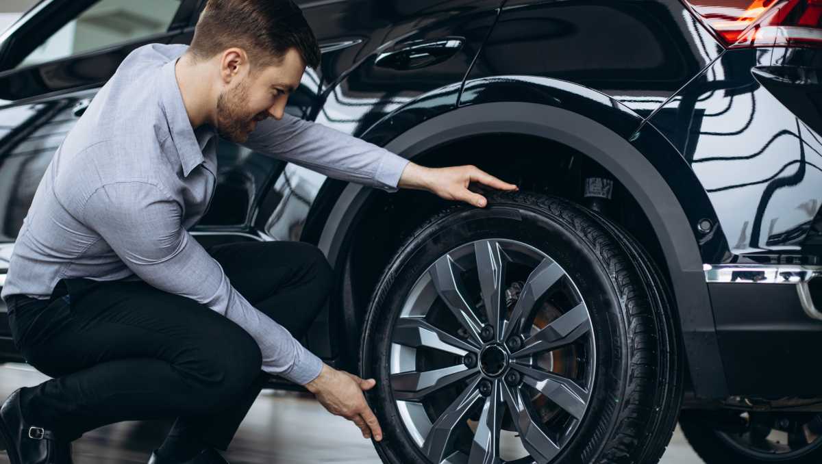 Hombre eligiendo neumáticos para su carro. | Freepik