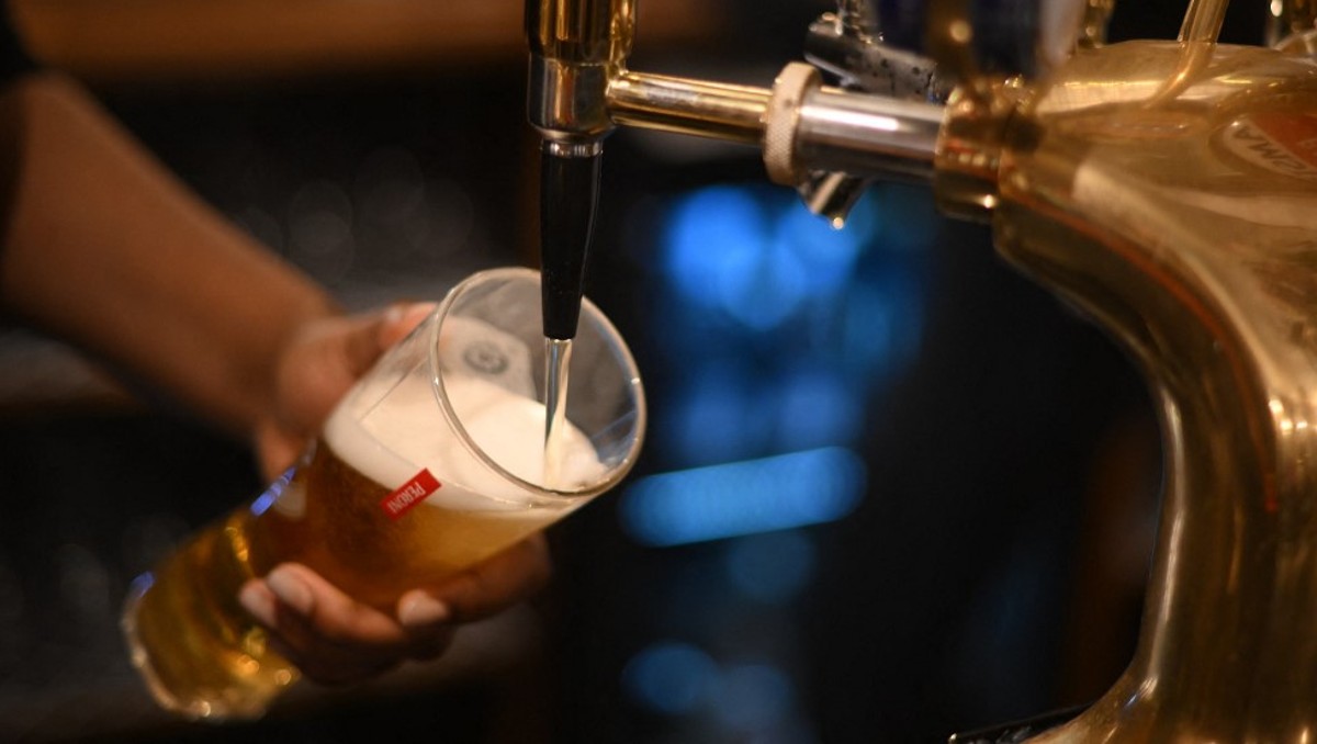 Hombre sirve cerveza. / AFP
