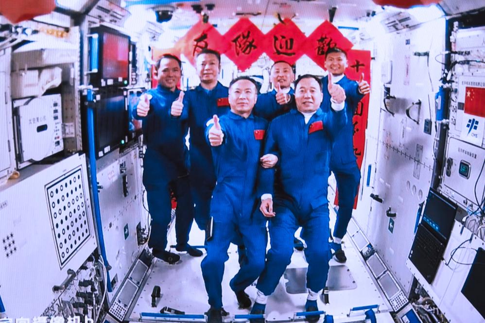 Tripulación de la Shenzhou-15 y la Shenzhou-16 mientras toman fotos del grupo en el interior de la estación espacial china. (Xinhua/Li Jie)