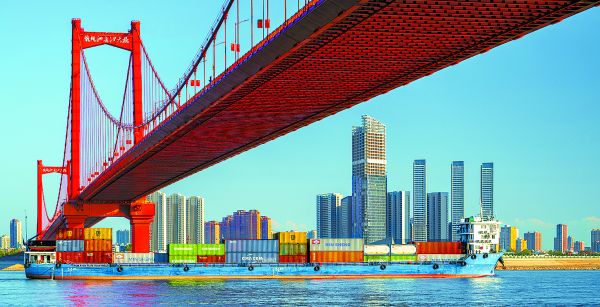Un buque de carga con contenedores pasa por el gran puente de Yingwuzhou, en Wuhan. SHUTTERSTOCK