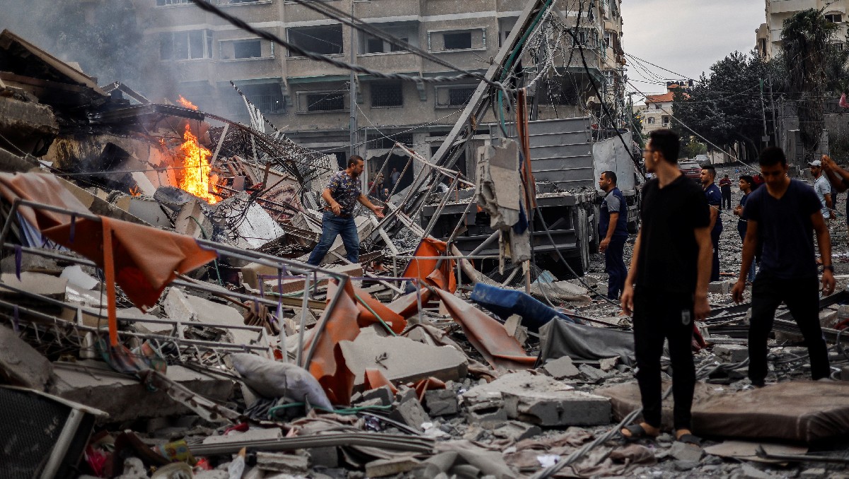 Palestinos junto a los restos de un edificio residencial destruido en Gaza. | Reuters