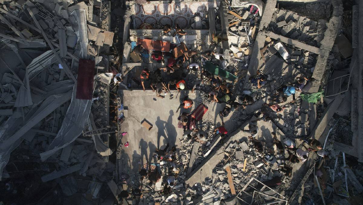 Palestinos inspeccionan los escombros de edificios alcanzados por un ataque aéreo israelí | (Agencia AP)