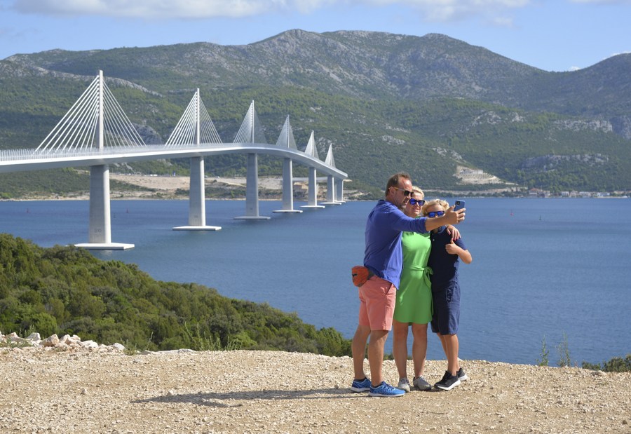 Un grupo de personas se toma fotos frente al puente Peljesac (construido en China) en Komarna, Croacia. 29 de agosto de 2023. (Xinhua/Li Xuejun)