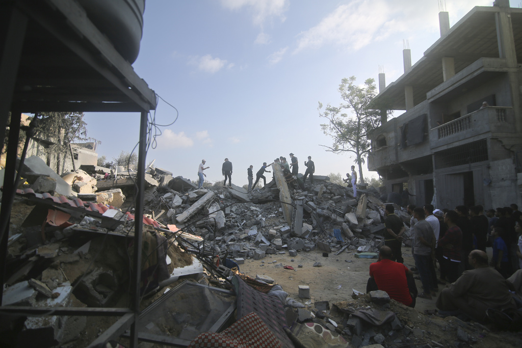 Un grupo de palestinos revisan los escombros de un edificio destruido por un ataque aéreo israelí en Rafah, en la Franja de Gaza | Agencia AP
