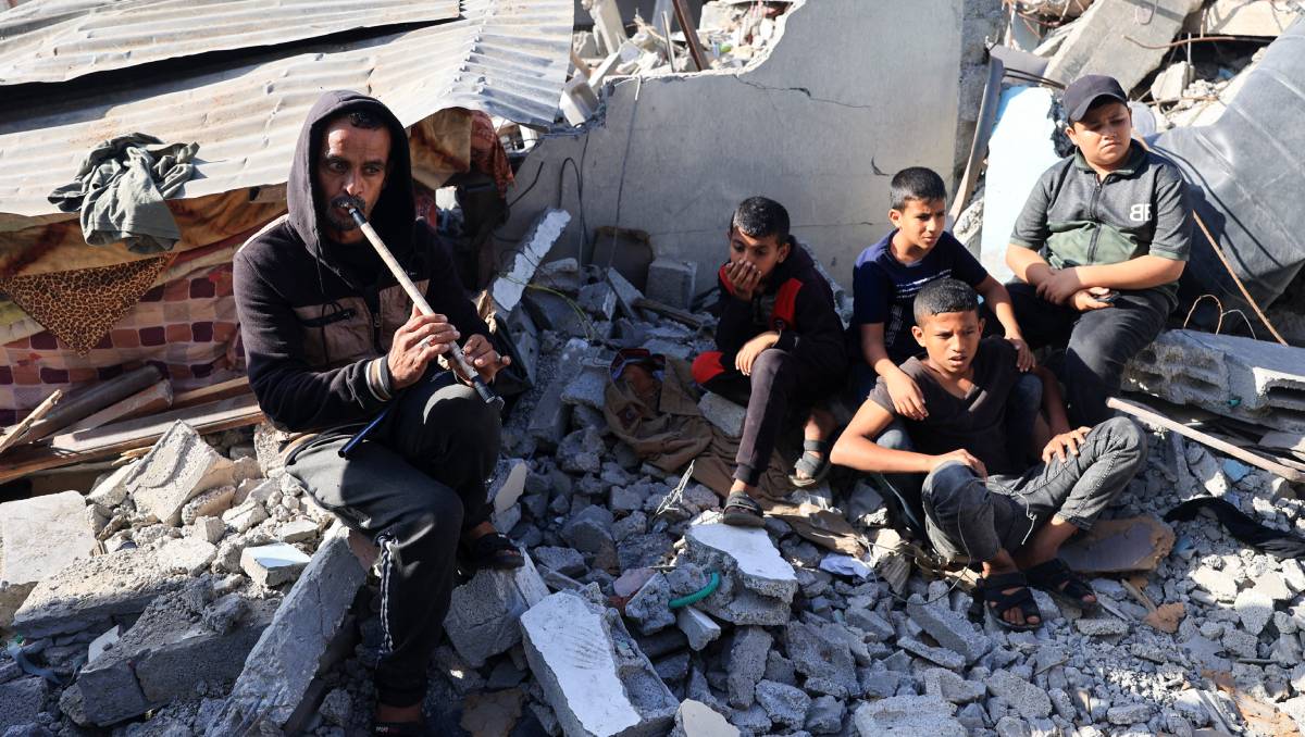 Un hombre toca la flauta para niños palestinos en Rafah | AFP