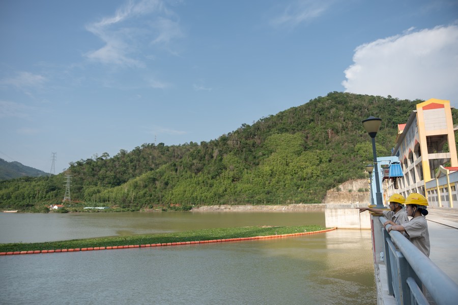 Nouphet Thongsakda (izquierda) y Phavady Nalathone charlan en la presa de la central hidroeléctrica Nam Ou 1 el 16 de junio de 2023. (Xinhua)