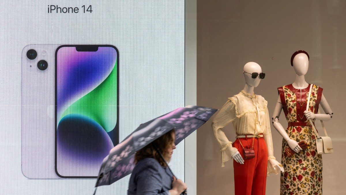 Una mujer con un paraguas pasa por delante de una pantalla de publicidad de Apple iPhone 14 en Moscú, Rusia. Mayo 2023. Foto: (Archivo)