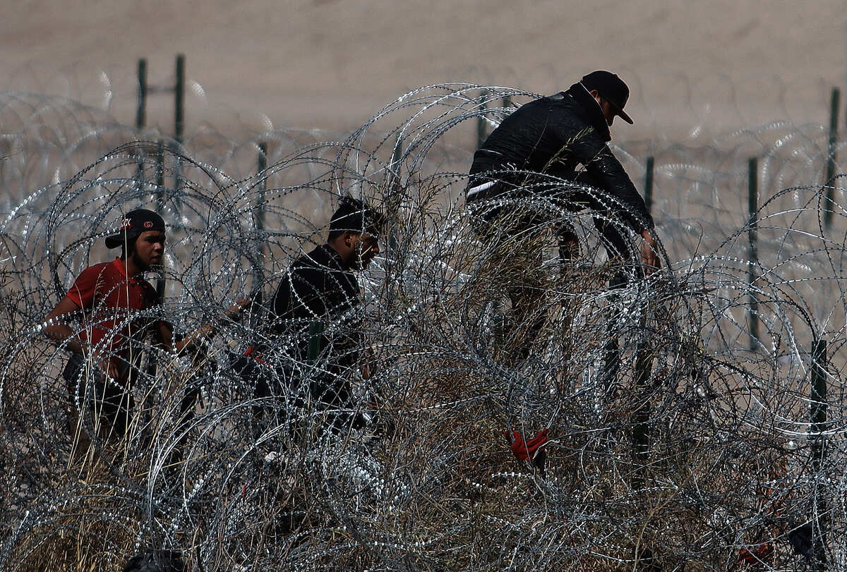 Migrantes intentan cruzar la cerca de alambres en la frontera que divide a México de los Estados Unidos | EFE