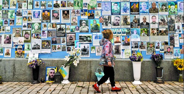 Una niña observa las fotografías de los soldados ucranianos muertos en la guerra contra Rusia en el Muro del Recuerdo. AP