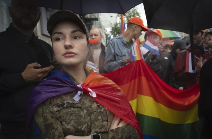 Una soldado, envuelta en una bandera LGBT, participa en la marcha del orgullo gay en Kiev, Ucrania, el 16 de junio de 2024. | Foto: AP