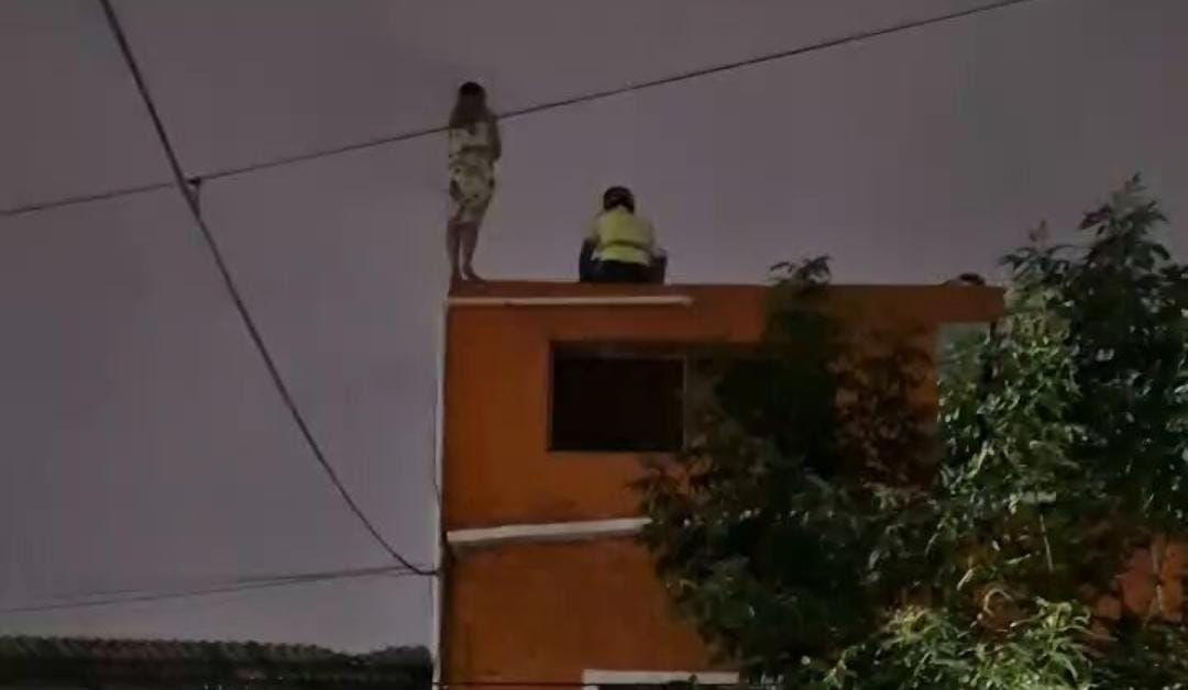 La mujer se paró a la orilla del edificio.