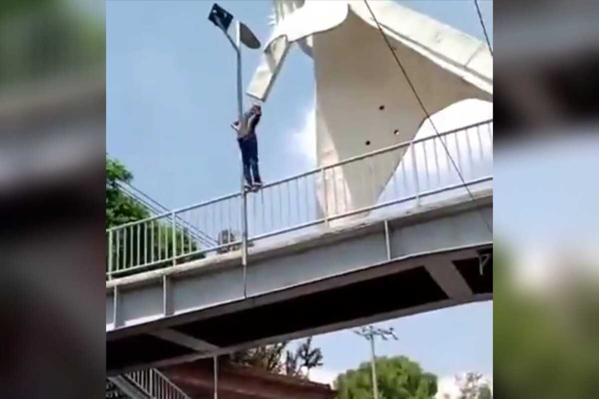 El hombre se columpiada en el poste de luz.