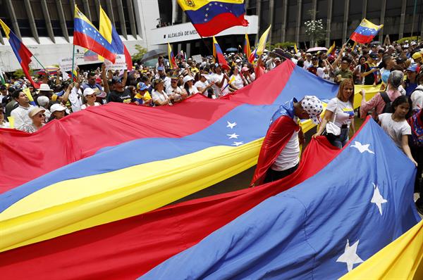 Personas sostienen banderas durante una manifestación en apoyo a los venezolanos tras elecciones | Foto: EFE