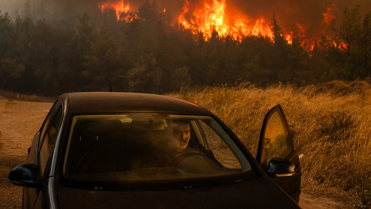 Una persona se sube a su coche frente a las llamas para evacuar durante un incendio forestal en Dione, Grecia, el 12 de agosto de 2024 | AP