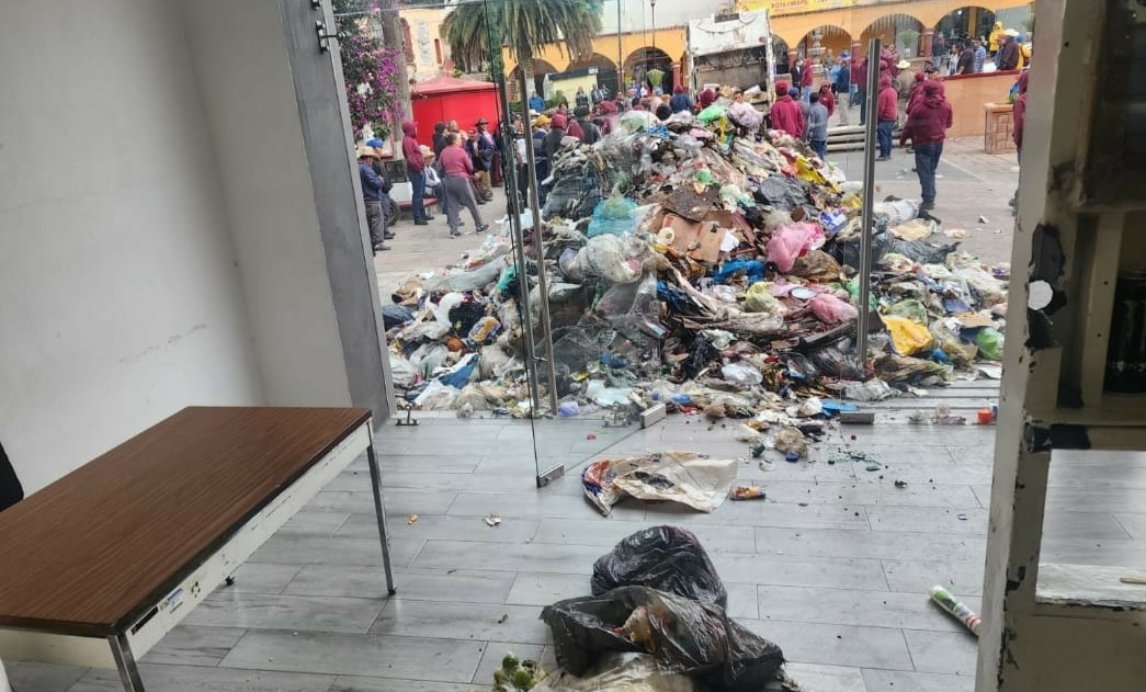 Trabajadores vacían dos camiones de basura en la presidencia municipal de Tepeapulco.