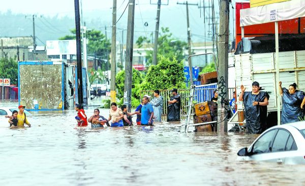 Personas caminan por las zonas inundadas de Acapulco. EFE