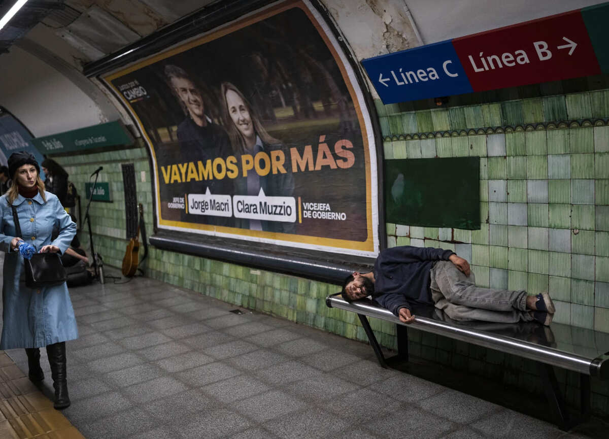 Una mujer camina en una estación de subterráneos de Buenos Aires, Argentina, mientras un hombre desamparado duerme en un banco | Foto: AP