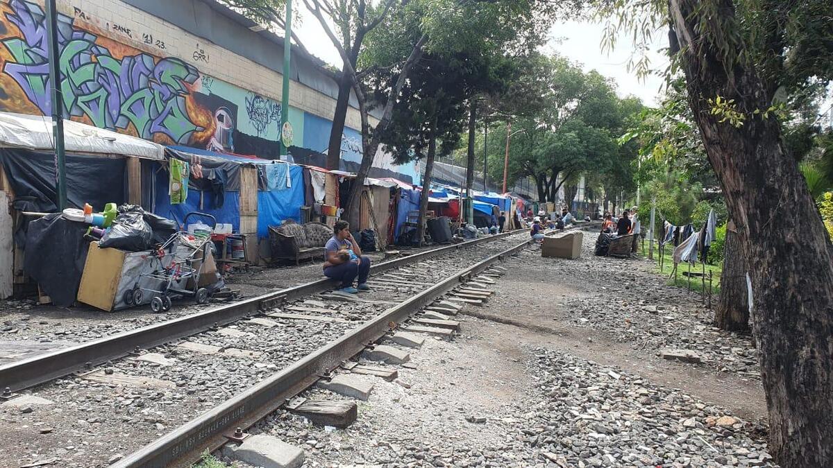 El campamento migrante se extiende por una pared llena de grafitis, a un costado de las vías de tren | Guillermo Osorno
